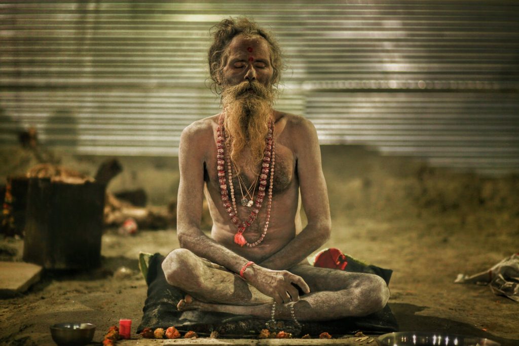 aghori sadhu meditating in sitting posture with garland beads in hands