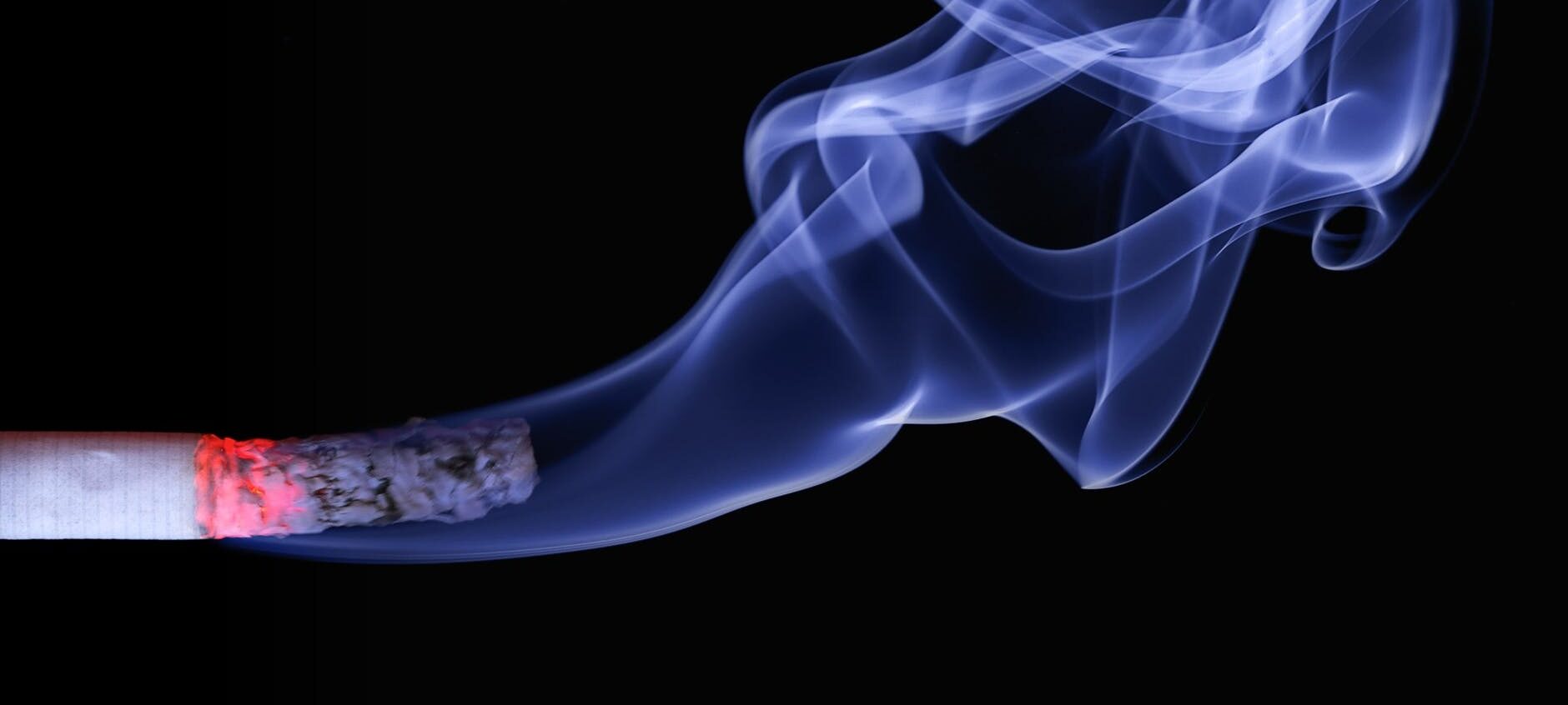 close up photo of lighted cigarette stick showing smoke fumes