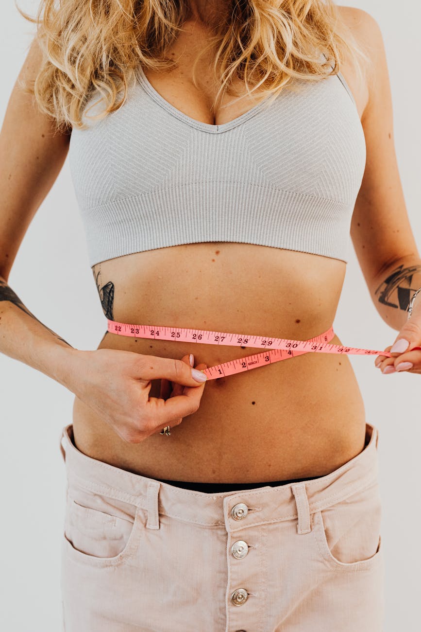 woman in sports bra holding a tape measure on her waist after following the Kapha diet.